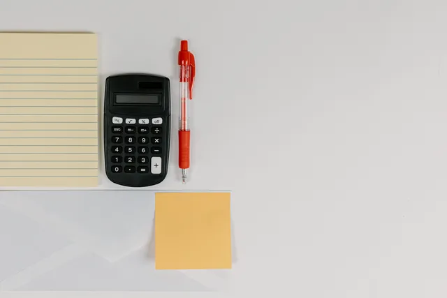 Top view of calculator, pen, and note pads arranged neatly on a white surface. Inside an accounts payable case study: one duplicate invoice, four fixes